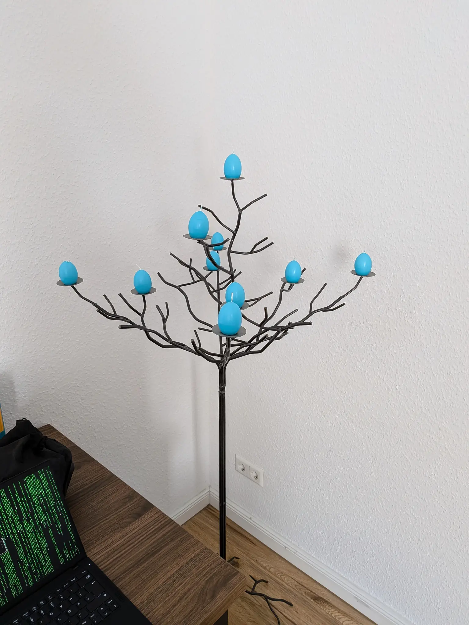 metal tree shaped candle stand with blue egg candles on it