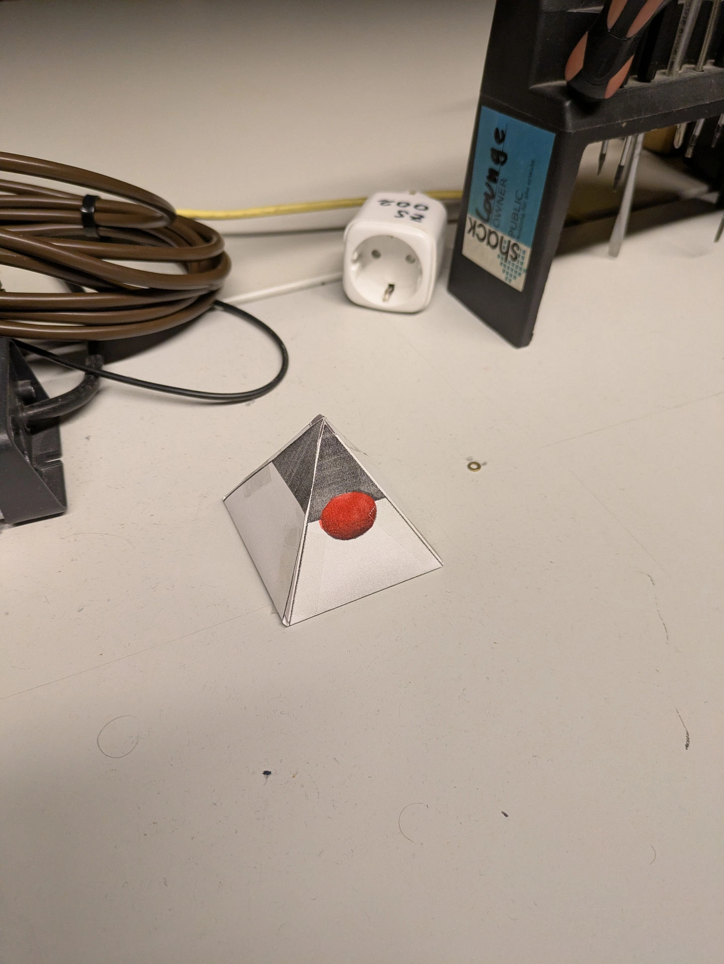 a duke prism sitting on a table, wires in the background